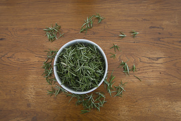 Fototapeta na wymiar Bowl with rosemary on a wooden table