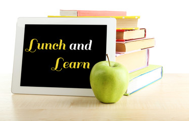 Books, PC tablet and apple on desk, isolated on white
