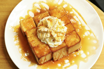 Honey bread toast with cream on white dish decorated on wooden table.