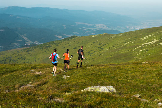 man and two women running in the Alps on the mountain trail