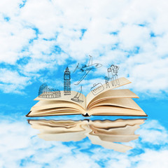 Open book with drawings on sky background