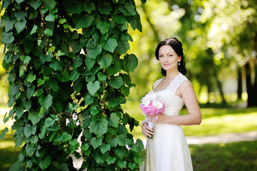 beautiful bride with a wedding bouquet on a background of green