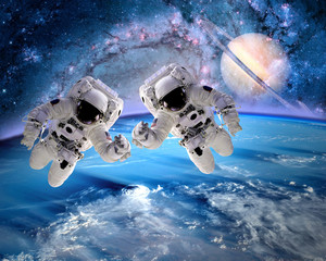 Two astronauts spaceman outer space saturn planet earth universe. Elements of this image furnished...