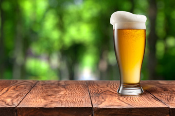 Beer in glass on wooden table against green