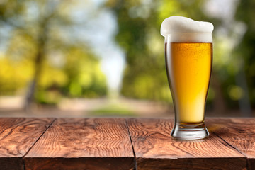 Beer in glass on wooden table against green