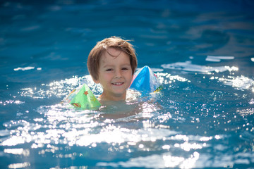 Fototapeta na wymiar Sweet little boy, swimming in big swimming pool