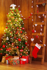 Decorated Christmas tree and ladder on wooden wall background
