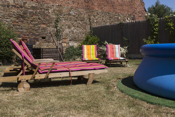 Four lawn chairs on the sun-drenched garden with colorful covers..