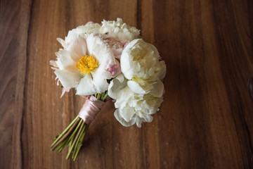 Bouquet of white flowers tied with a pink ribbon on a black chair.