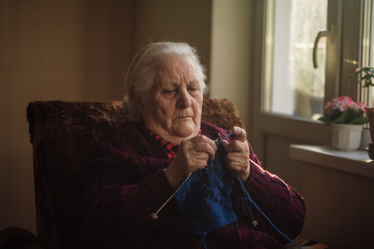 The old woman sits at home and knits garments