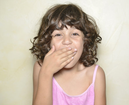 Ni&ntilde;a tap&aacute;ndose la boca sorprendida