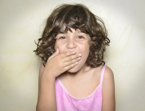 Ni&ntilde;a tap&aacute;ndose la boca sorprendida