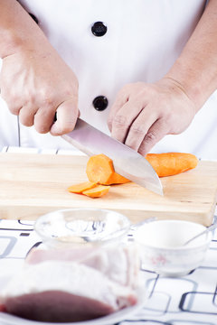 Chef cutting carrot on wooden broad