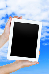 Hands holding tablet PC on sky background