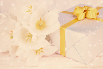 Beautiful bouquet of white tulips and gift box on table on light background