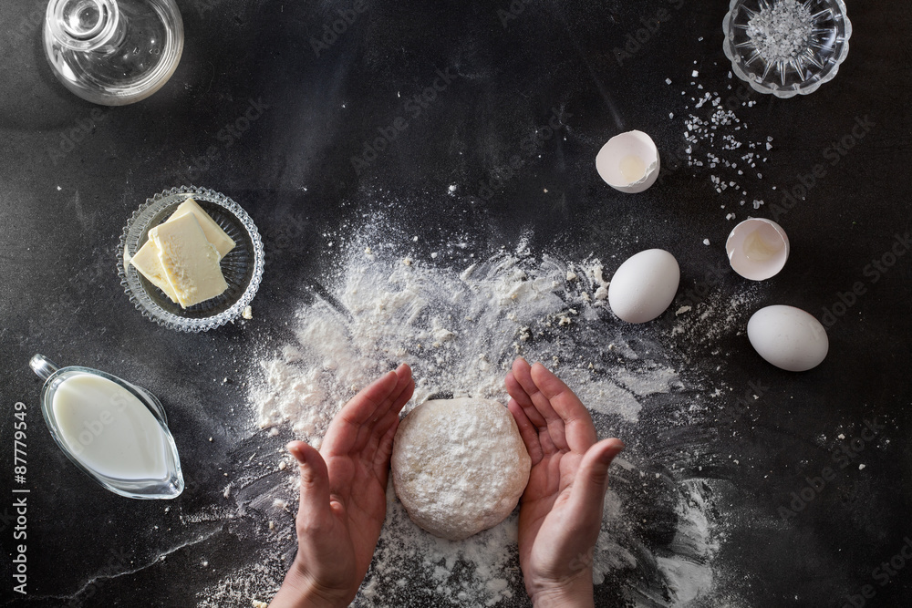 Wall mural woman's hands knead dough on table with flour