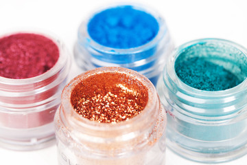 Set of glass jars with metallic glossy eye shadows on white