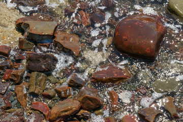 Close-up of wet red stones in foam bubbles as background.