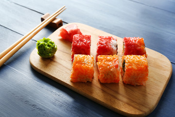 Sushi rolls on tray on color wooden background