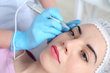Obraz na płótnie Canvas Cosmetologist applying permanent make up on eyes, close-up