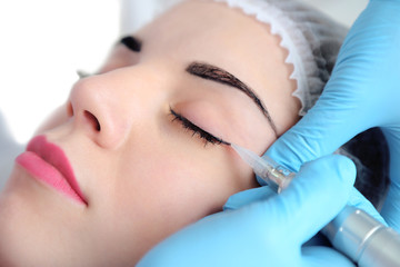 Cosmetologist applying permanent make up on eyes, close-up