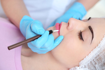 Obraz na płótnie Canvas Cosmetologist applying permanent make up on lips