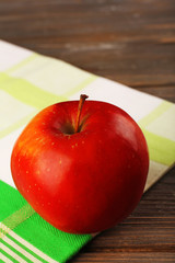 Apple with napkin on wooden table, closeup