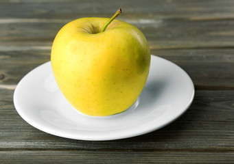 Apple on saucer on wooden background