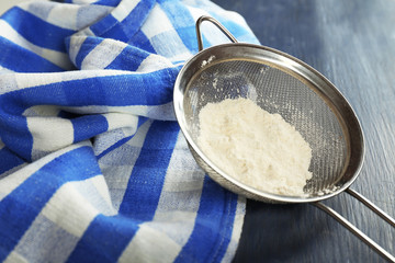 Sifting flour through sieve on wooden table, closeup