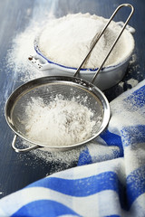 Sifting flour through sieve on wooden table, closeup