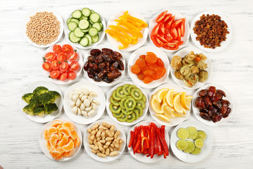 Different products on saucers on wooden table, top view