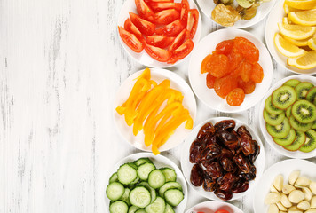 Different products on saucers on wooden table, top view