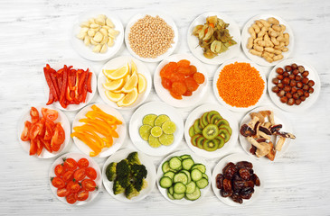 Different products on saucers on wooden table, top view