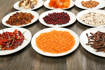 Different products on saucers on wooden table, closeup