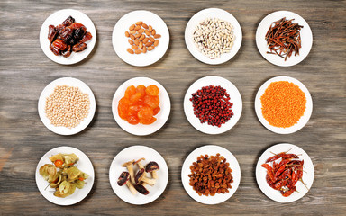 Different products on saucers on wooden table, top view