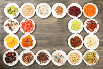 Different products on saucers on wooden table, top view