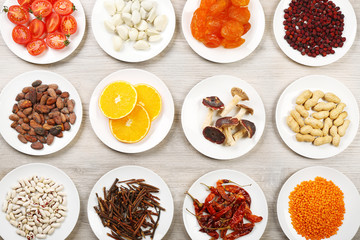 Different products on saucers on wooden table, top view