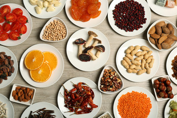Different products on saucers on wooden table, top view