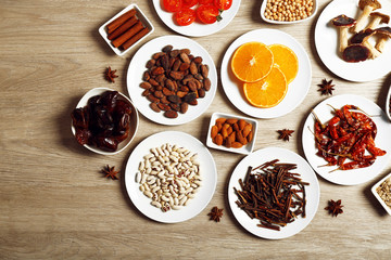 Different products on saucers on wooden table, top view