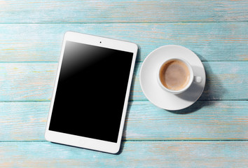 Cup of coffee and tablet on wooden table. Preparing for travel,reservation ticket