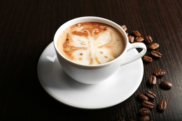 Cup of latte art coffee with grains on wooden background