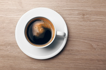 Cup of coffee on wooden table, top view