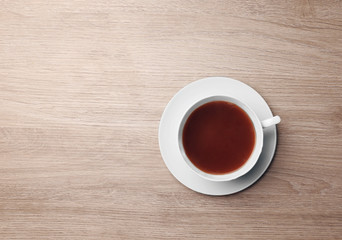 Cup of coffee on wooden table, top view