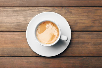 Cup of coffee on wooden table, top view
