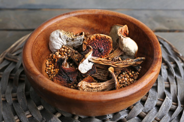 Dried mushrooms in bowl on wicker mat, closeup