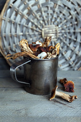 Dried mushrooms in metal cup on wooden background