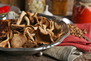 Dried mushrooms in metal tray with spices on wooden table, closeup