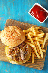 Tasty burger and french fries on wooden table background  Unhealthy food concept