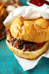 Tasty burger and french fries on wooden table background  Unhealthy food concept