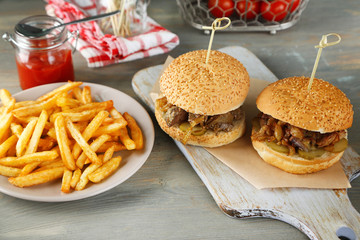 Tasty sandwiches and french fries on plate, on wooden background. Unhealthy food concept